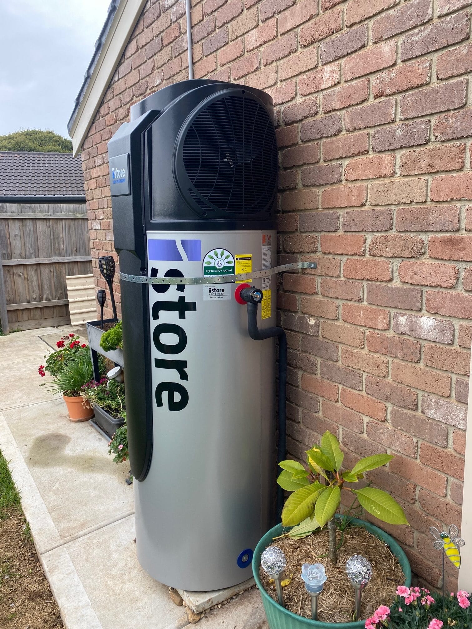 iStore heat pump hot water system installed on a brick wall