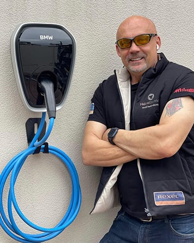 Helcro Electrical technician next to a wall-mounted BMW EV charger installation