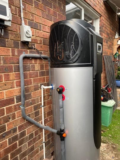 Heat pump hot water system installed against a brick wall